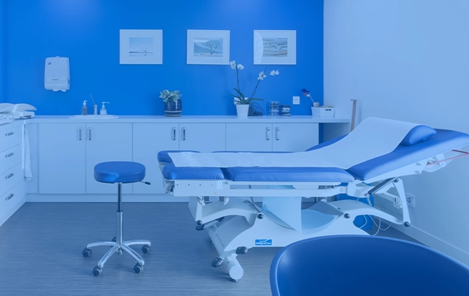 Un cabinet médical propre et moderne avec un lit d'examen et un mur bleu.