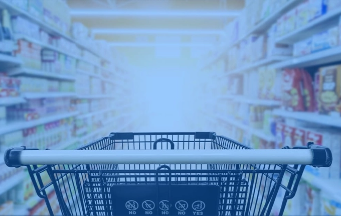 Une vue en perspective de l'allée d'un supermarché depuis un caddie, avec un filtre bleu.