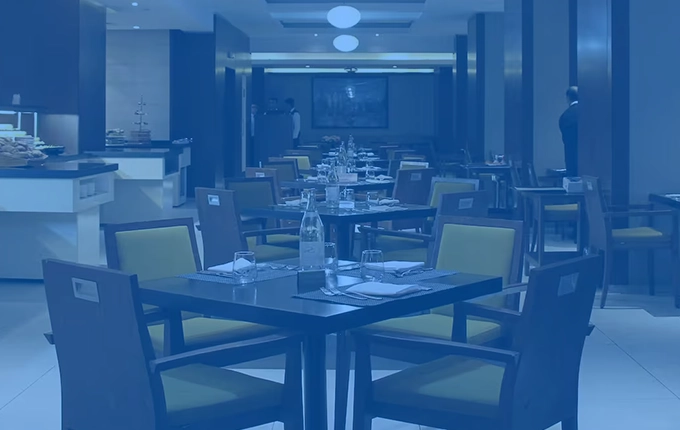 Une salle de restaurant chic et formelle avec des tables dressées et des chaises, teintée en bleu.
