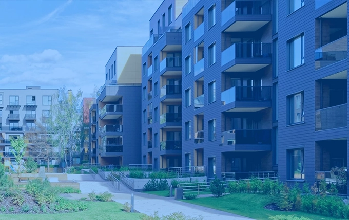 Un immeuble d'appartements moderne avec des balcons donnant sur un parc verdoyant, teinté en bleu.